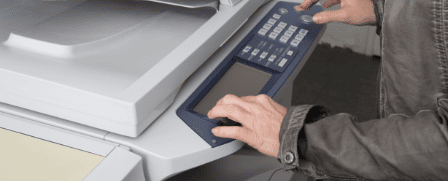 Ein Mitarbeiter bedient einen Multifunktionsdrucker und bedient das digitale Eingabefeld.