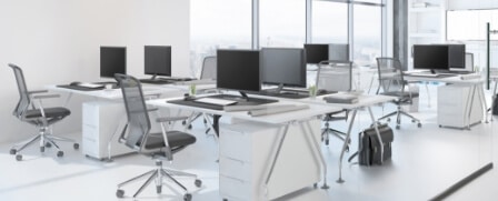Ein leeres Büro mit zahkreichen Bürotischen. Darauf befinden sich Bildschirme, Maus und Tastatur.