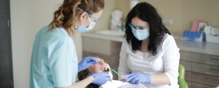 Eine Frau liegt auf einem Zahnarzt Stuhl und wird gerade behandelt.