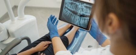 Eine Zahnärzting bespricht gerade das Röntgenbild mit ihrem Patienten.