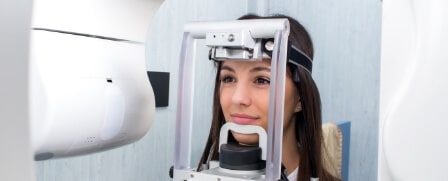 Eine junge Frau befindet sich im Röntgenzimmer. Ihre Zähne werden gerade untersucht.